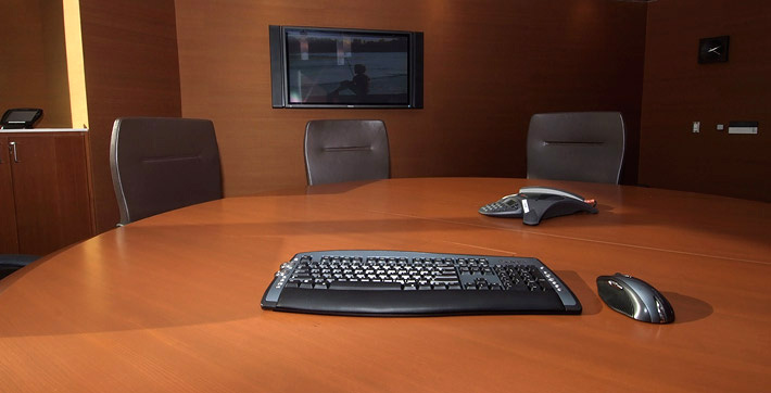 Photo of wireless computer keyboard and mouse and Polycom system on the table facing the TV screen