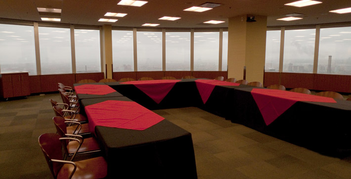 Photo de la Salle de conférence où les tables, décorées de nappes noires, sont disposées en U et peuvent accueillir 24 personnes
