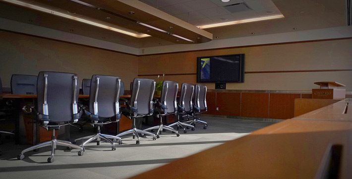Photo de la Salle multimédia, qui présente un décor de salle de conférence où des sièges pour 14 personnes sont disposés autour de la table