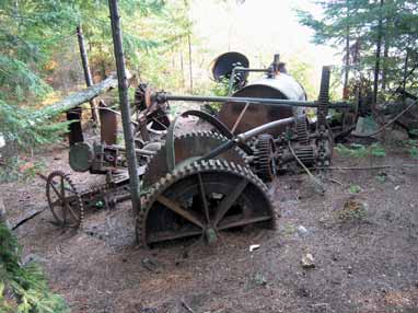 Photograph depicts peices of machinery in a forest.