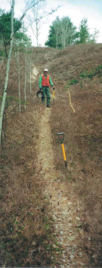 photogrpah of a worker standing on a trail on a hill