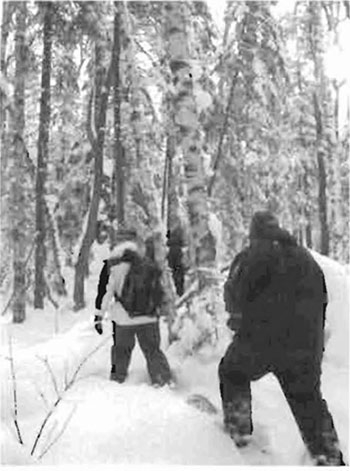 the photo of two men snowshoeing on snow during winter site visit.