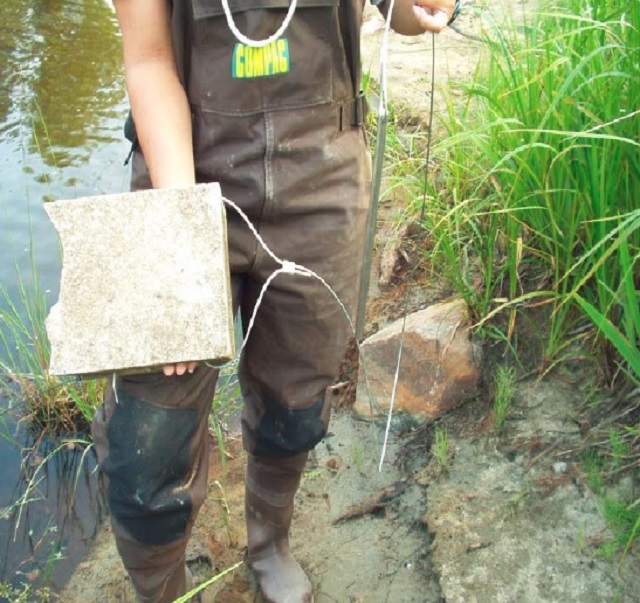 Colour photo of a person holding a tethered half cinder block.