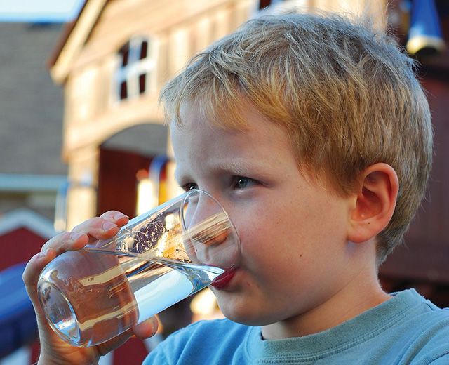 Photo d’un garçonnet buvant un verre d’eau potable.