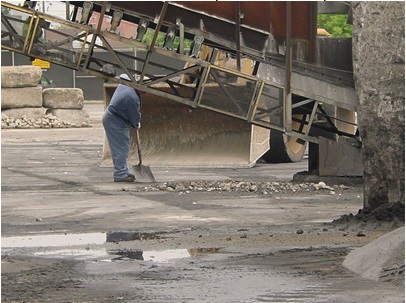 This picture shows a person cleaning up deposited fugitive materials spilled on the ground to prevent further dispersion.