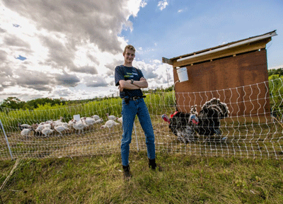 Photo of Josiah Lodewyk , founder of Tasty Turkeys, standing in front of his turkey farm.