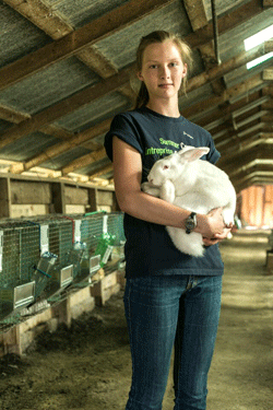 Photo of Mattea Lodewyk, founder of Rapha Ridge Rabbitry, holding a rabbit.