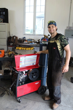 Photo of Keigan Goetz, founder of Goetz Fabricating, pictured with his welding equipment.
