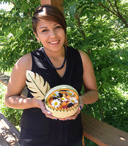 Photo of Tina Square, founder of Tasty Creations, holding a sample of her fruit creations, a carved melon with fruit balls and daisies inside.