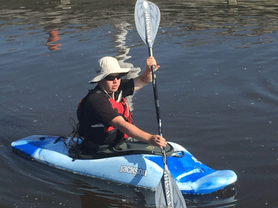 Photo of Cavan Laferriere, founder of Temiskaming Kayak Academy, holding a kayak and a paddle.