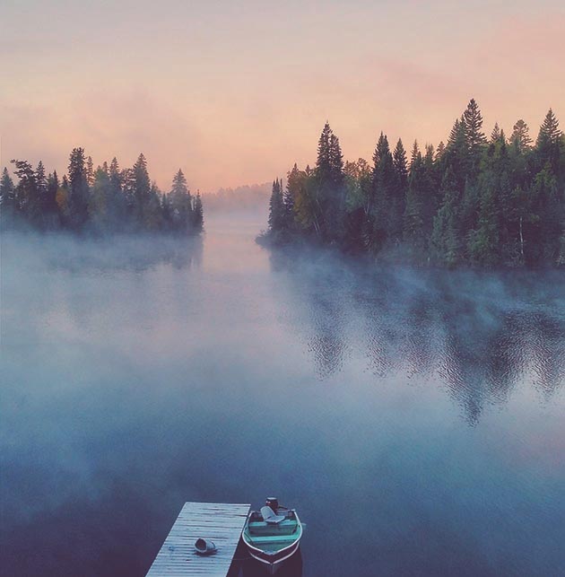 Morning mist rising from a lake with a forested shoreline