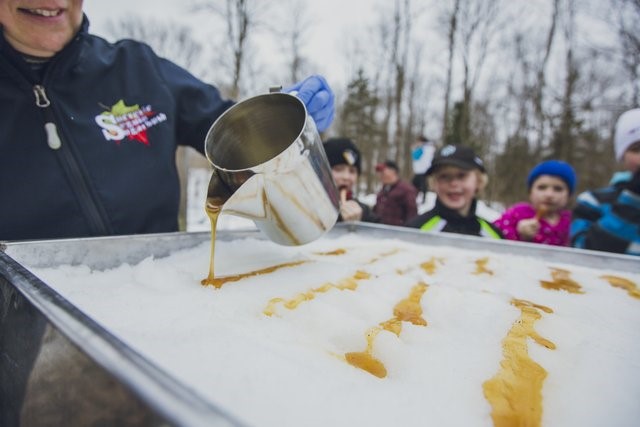 Photograph of a person pouring syrup over snow at Seguin Maple Bush