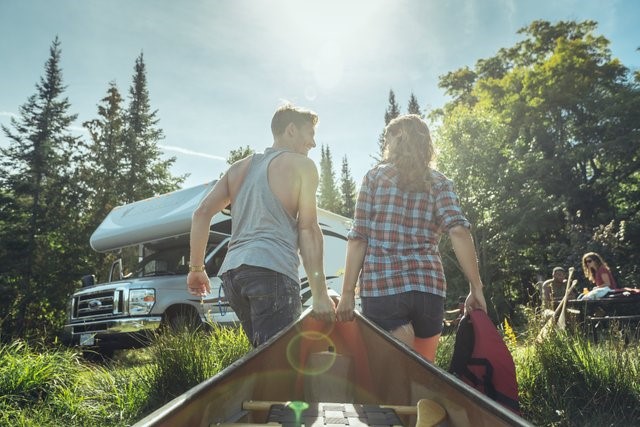 Photograph of two people dragging a canoe to a camper at Algonquin Provincial Park