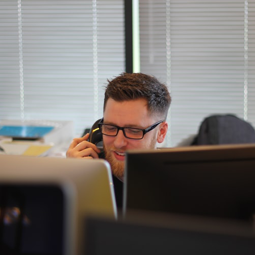 A person sitting at a desk talking on the phone in an office setting.