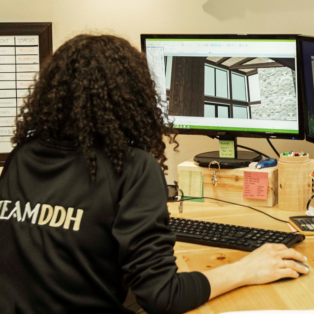 Une personne assise à un bureau devant un ordinateur, en train de concevoir un bâtiment.