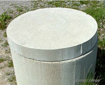 Figure 12-15 is a photograph of a dug well with a solid well cover.
