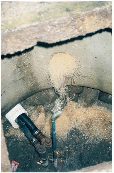 Figure 11-10 was taken looking into a well pit. The concrete tile of the well pit is shown in the centre and upper portion of the photograph. The floor of the well pit consists of gravel and broken limestone bedrock. The sanitary seal of the top of the drilled well is located flush with the floor of the well pit. Two waterlines and an air vent extend out of the drilled well’s sanitary seal. There is an open hole in the well pit’s concrete tile. A white to tan coloured fungus (foreign material) has been allowed to grow in the pit from the concrete hole and onto the floor. The fungus is also an indicator that surface water can enter the pit. If surface water fills up in the well pit, it could migrate through the air vent and into the well. Fungus and other foreign materials can potentially migrate from the pit into this drilled well that is used for human consumption.