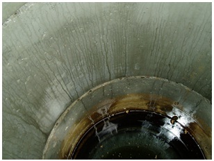 Figure 11-3 shows the inside view of a well. Water is seeping through the unsealed joints between concrete well casings. The water is leaving marks on the concrete tiles as it moves. The unsealed joints are allowing surface water and other foreign materials, potentially containing potential pathogens, to enter the well and impair the quality of the well water. At the bottom of the photograph, the top of the water level is observed. There is debris and other foreign material floating on top of the water that may impair the quality of the well water.