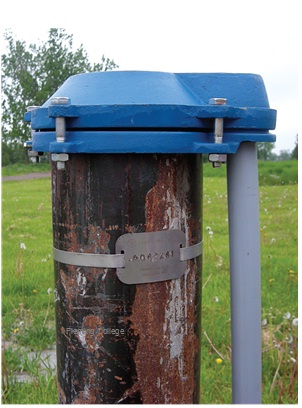 Figure 13-23 shows the same well after the well cap and conduit pipe was upgraded and the broken well tag replaced with a new one.