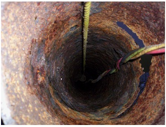 Figure 15-21 show the interior of a drilled well with casing corroded to a point that a significant hole has formed through the well casing. The hole is seen on the right side.