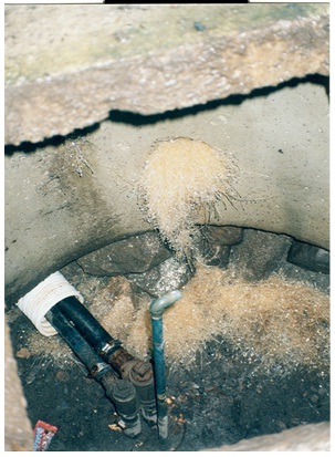 Figure 15-26 shows two waterlines, an air vent and a sanitary well seal which need to be removed from the top of well casing located on the floor of this well pit.