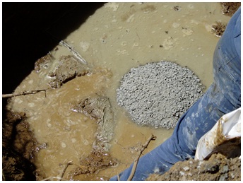 Figure 15-44 shows bentonite pellets being placed in the well opening (excavation) on top of abandonment barrier material (bentonite) in a drilled well (see Figure 15-43).