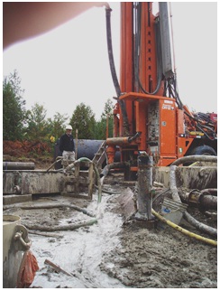Figure 15-53 shows the concrete being pumped at a high rate into the flowing well from Figure 15-49. The concrete is displacing the remaining water in the well. The water is discharging from the well onto the surface and into a controlled sediment settling area.