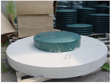 Figure 9-21 shows the green coloured access lid is sealed to the top of the concrete cover using a butyl joint non toxic sealing material (mastic sealing material). An opening (not shown) exists in the centre of the concrete. The top of the access lid is affixed to the access lid riser using screws. The access lid and remaining well cover must prevent the entry of surface water and foreign materials from entering the well.