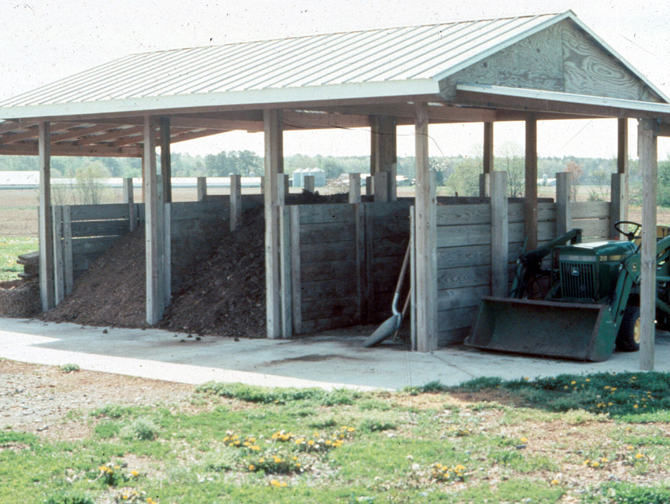 Photo d’un système à trois silos-couloirs surmontés d’un toit et servant au compostage de matières organiques.