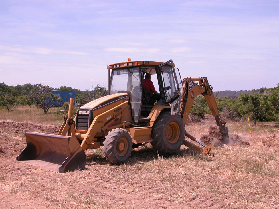 Picture of a backhoe digging a burial pit in a field