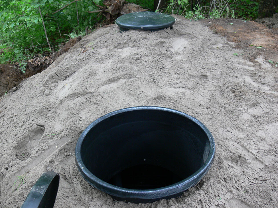 This is a picture of a black plastic octagonally-shaped disposal vessel lying on its side at a shop. It is about the height of a man.