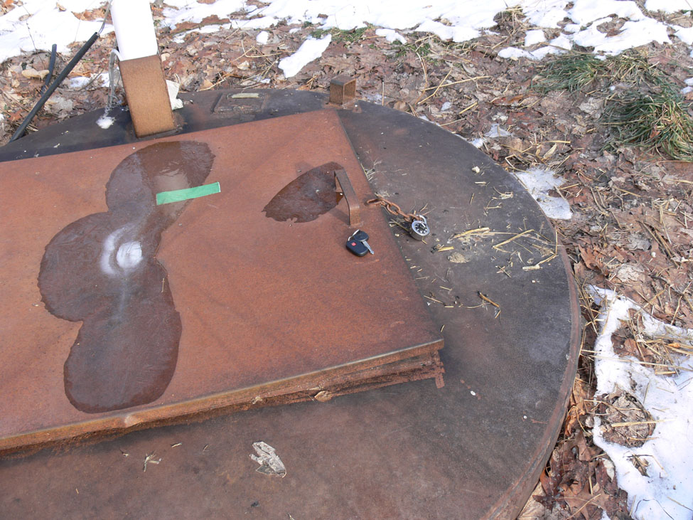 This picture is taken from about one metre above a steel disposal vessel in winter time showing the access hatch closed and locked with a combination lock. The vessel is about 2 m in diameter.