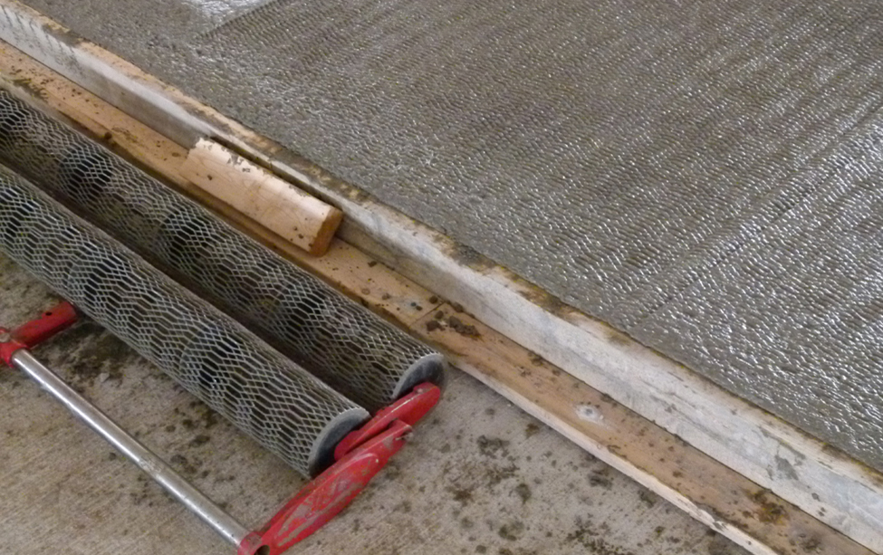 Figure 1. Jitterbug concrete roller head sitting on floor. Roller head is made of two patterned cylinders side by side.