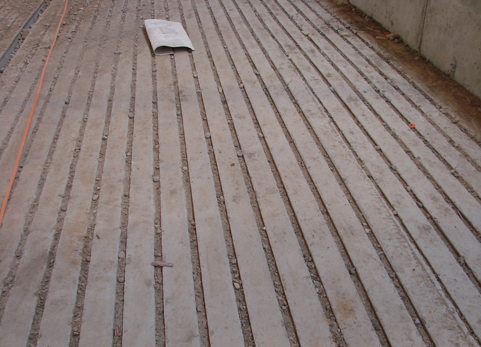 Section d’un revêtement de plancher de béton dans une étable laitière, comportant des rainures espacées également et taillées en lignes droites dans le revêtement, d’une extrémité à l’autre.