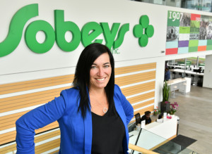 C'est une photo de Sheri Evans debout devant un panneau-réclame de Sobeys. Elle est directrice du développement local, responsable du marchandisage en Ontario pour Sobeys Ontario, et doit faire en sorte que les petits et moyens fournisseurs peuvent approvisionner les magasins à une échelle régionale.