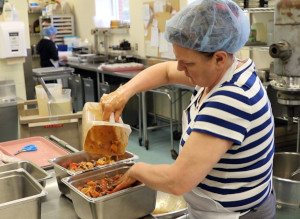 C'est une photo d'une employée du service alimentaire préparant un ragoût au bœuf et aux légumes pour les patients hospitalisés dans la cuisine de l'Hôpital Grand River à Kitchener. Le ragoût est fait avec du bœuf de l'Ontario provenant de VG Meats et des légumes racines de l'Ontario d'autres exploitations agricoles locales.