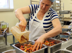 C'est une photo d'une employée du service alimentaire préparant un ragoût au bœuf et aux légumes pour les patients hospitalisés dans la cuisine de l'Hôpital Grand River à Kitchener. Le ragoût est fait avec du bœuf de l'Ontario provenant de VG Meats et des légumes racines de l'Ontario d'autres exploitations agricoles locales.