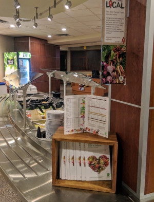 This is a picture of communication tools placed at St Paul's University College's Wheelock Dining Hall at the University of Waterloo. The communication tools shown are the Foodland Ontario Nutrition Guide featuring a heart-shaped cornucopia of Ontario food and signage about Chartwells Buy Local Program featuring a cornucopia of Ontario vegetables. Chartwells is making communication tools co-branded with the Foodland Ontario logo available to colleges, universities and schools to promote local food on their campuses.