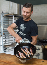 C'est une photo de Mike McKenzie avec un couteau à la main et qui prépare des viandes artisanales faites à la main. Mike McKenzie est le fondateur de Seed to Sausage, une entreprise de l'Est ontarien qui fabrique des viandes salaisonnées artisanales.