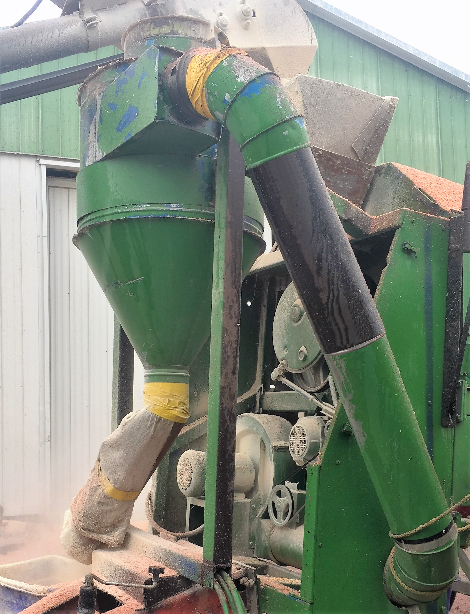 A cyclone separator, like the unit pictured on a grain cleaner system, uses rotational effects and gravity to remove particulate matter from an air stream