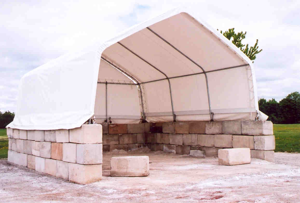 Photo d’une structure de stockage de sable ouverte sur le devant, avec trois parois et un toit.