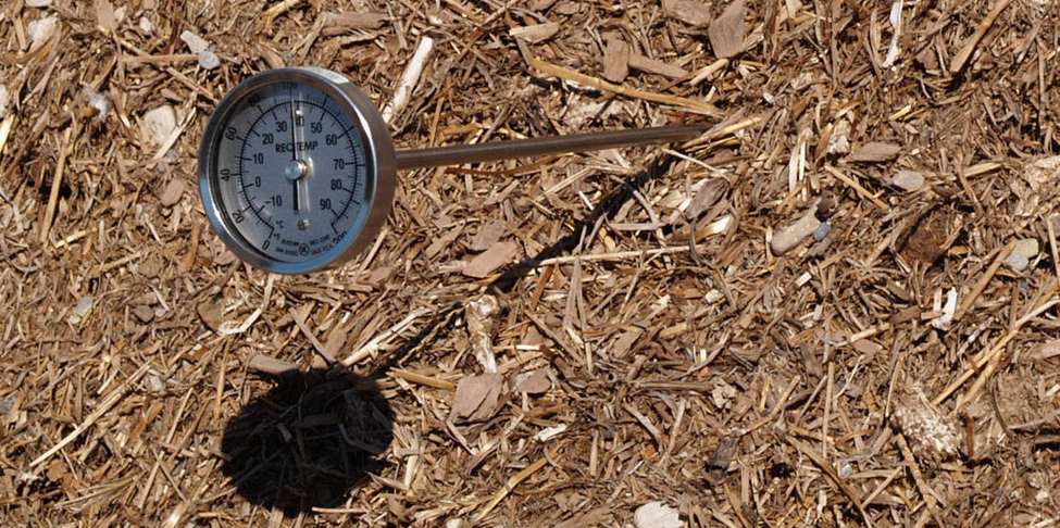 Un thermomètre circulaire placé dans un tas de compost.