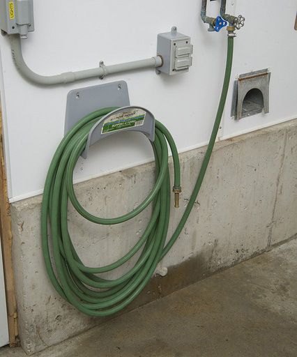 green hose coiled and mounted on wall