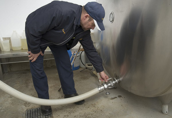man attaching a hose to a bulk milk tank