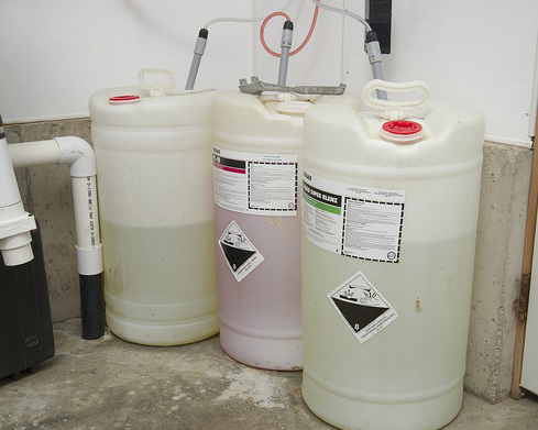 three large plastic barrels of cleaning fluids