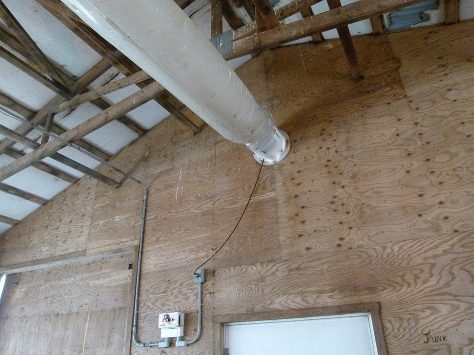 Air tube and fan attached to the end of a barn wall.