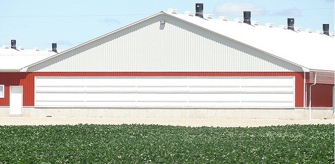 Photo d'un mur d'extrémité d'un bâtiment d'élevage montrant de gros panneaux en position fermée sur les prises d'air d'un système de ventilation longitudinale.