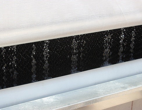 Close-up picture of an evaporative cooling pad with water trickling down the exterior surface of the pad material.