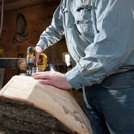 photo of woodworker working on a tree trunk within a workshop