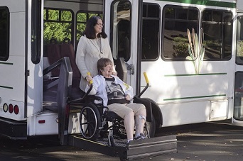 Woman in wheelchair exiting accessible bus.